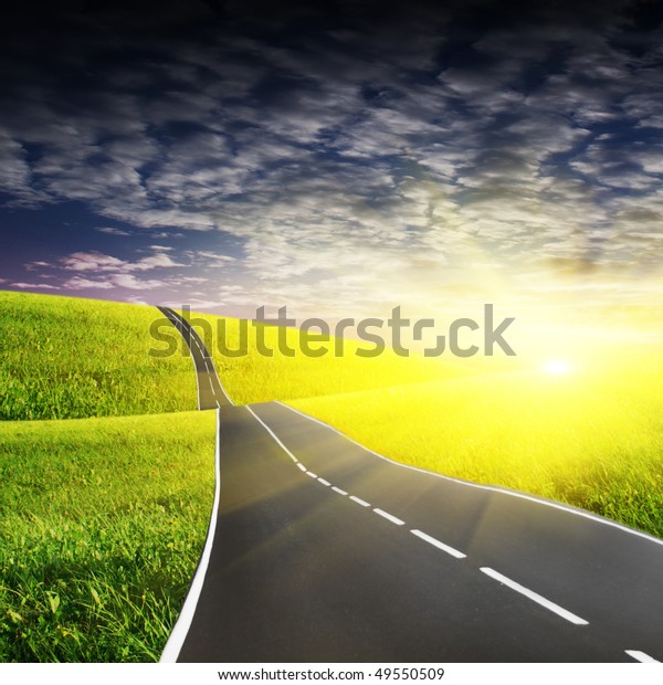 Green field and road at\
sunset.