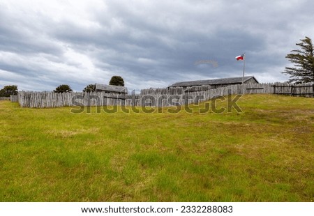 Green Field, Wood Fence and Old Log Building at Fuerte Bulnes, Famous Historic Chile Fort on the Strait of Magellan near Punta Arenas, Chilean Patagonia, South America
