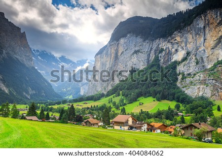 Green fields and famous stunning touristic town with high cliffs in background,Lauterbrunnen,Bernese Oberland,Switzerland,Europe