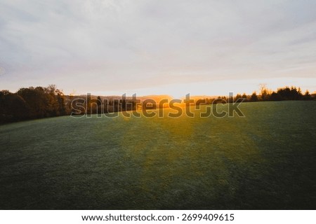 Green fields and vibrant fall trees in the early morning sun.