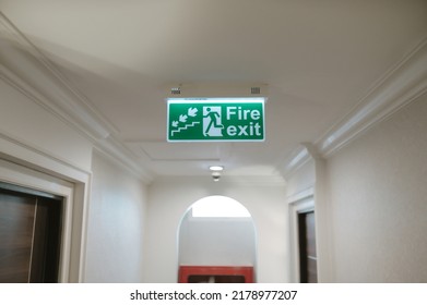 Green fire escape sign hang on the ceiling in the hotel.