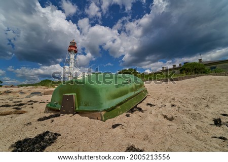 Green fishing boat on sand with blue sky and water