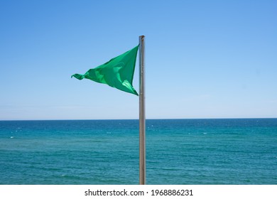 Green Flag On Beach With Sea In Background