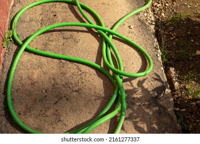 Green flexible hose for watering garden. Water supply. Tangled wire.