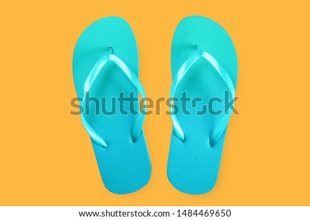 Green flip flops isolated on yellow background. Top view. Flat lay