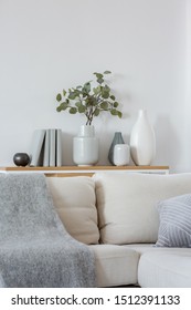 Green Flowers In Grey Vase Next To Books On Wooden Console Table In Bright Living Room Interior