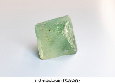 Green Fluorite Octahedron rough crystal closeup on neutral background.