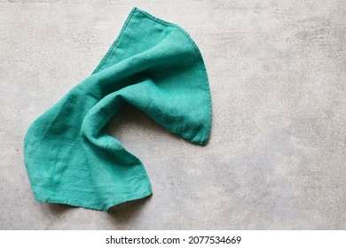 Green folded linen napkin on gray concrete table with copy space, top view