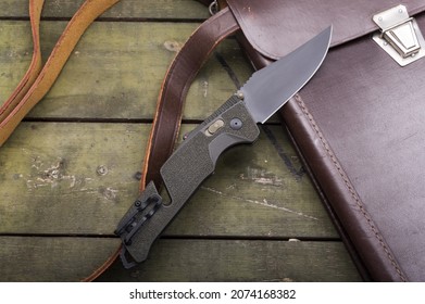 Green folding army knife. Knife with a black blade. Knife and army briefcase.