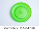 A green frisbee is sitting on a white background. The frisbee is the only object in the image