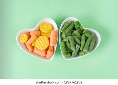 Green Frozen Asparagus Beans, Baby Carrot Mix In White Heart-shaped Bowl, Light Green Background. Concept Love Vegetables, Vegetarian Food. Diet Ingredient. Healthy Meal Prep To Freezer Blank