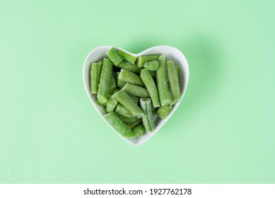 Green Frozen Asparagus Beans In A White Heart-shaped Bowl On Light Green Background. Concept Love Vegetables, Vegetarian Food. Diet Ingredient. Top View. Healthy Meal Prep For Freezer Blank. 