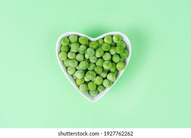 Green Frozen Peas In A White Heart-shaped Bowl On Light Green Background. Concept Love Vegetables, Vegetarian Food. Diet Ingredient, Top View. Healthy Meal Prep For Freezer Blank