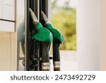 Green fuel pump nozzles at gas station for vehicles refueling with gasoline or diesel