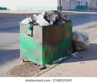 Green garbage container full of stuff