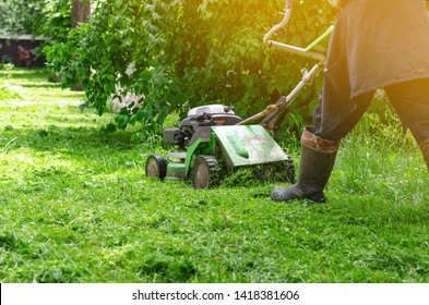 Green gasoline lawn mower on the grass in the park on the lawn. - Shutterstock ID 1418381606