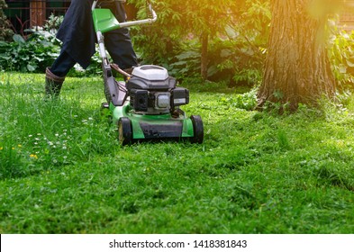 Green gasoline lawn mower on the grass in the park on the lawn. - Shutterstock ID 1418381843