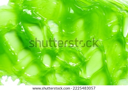 Green gel slime, cosmetic product as background, skin care mask or peeling gel texture swatch.