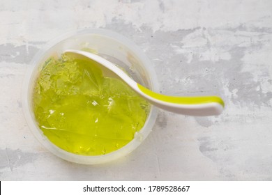 green gelatin in plastic box with spoon