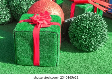 Green gift box with red bow on artificial green grass background. Christmas and New Year concept - Powered by Shutterstock