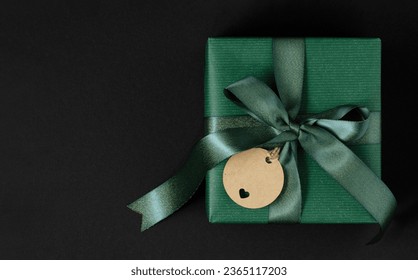 Green gift box with green ribbon and craft brown gift tag. Green background, place for your text - Powered by Shutterstock