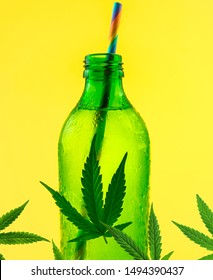 Green glass bottle with Cannabis CBD infused Water lemonade with cannabis leafs isolated on yellow