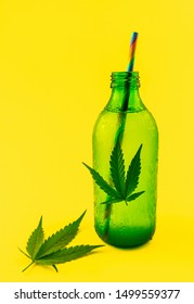 Green glass bottle with Cannabis CBD infused Water lemonade with cannabis leafs isolated on yellow