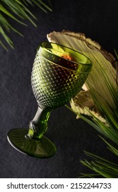 Green glass goblet with red wine on a background of wood and foliage. The concept of ecological table setting. vertical position