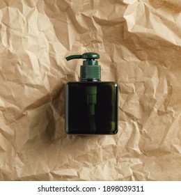 Green Glass Soap Dispenser Bottle On Crumpled Paper, Top View.