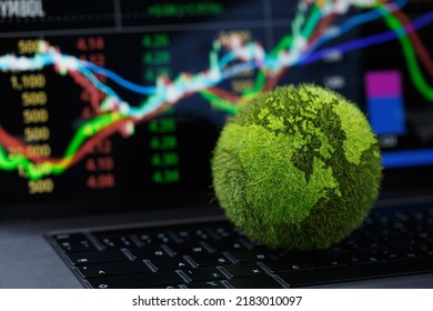 Green Globe on laptop keyboard with Stock graph on the laptop screen. Green business concept. Carbon efficient technology. Digital sustainability. future green energy innovation business trend. - Powered by Shutterstock