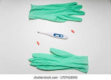 Green Gloves, Electronic Termometer And Pills On The White Background