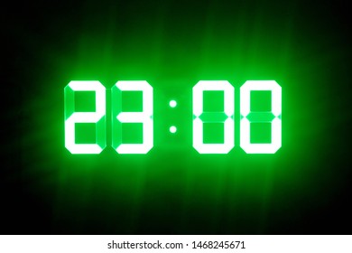 Green glowing digital clocks in the dark show 23:00 time - Powered by Shutterstock