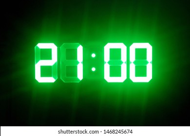 Green glowing digital clocks in the dark show 21:00 time - Powered by Shutterstock