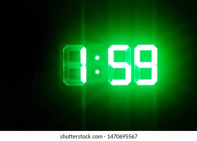 Green glowing digital clocks in the dark show 1:59 time - Powered by Shutterstock