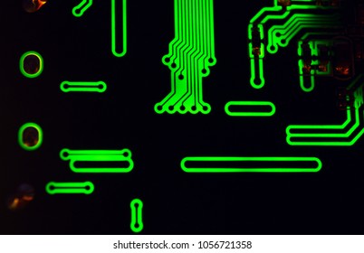 Green glowing lines on computer motherboard close-up in dark.