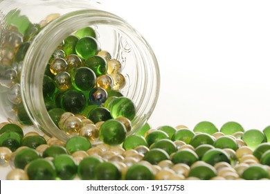 Green And Gold Marbles Spilling Out Of A Jar.