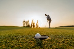 Green, Golf, Ball, Club, Course, Grass, Sport, Golfing, Fairway. Golf Ball Putting Player, Golf Ball Spinning To The Hole On The Green Of The Golf Course With The Early Light Of Sunset.