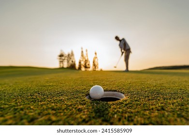green, golf, ball, club, course, grass, sport, golfing, fairway. golf ball putting player, golf ball spinning to the hole on the green of the golf course with the early light of sunset.