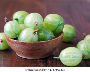Green gooseberries in wooden bowl (Ribes uva-crispa)