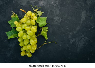 Green grapes with leaves of grapes on a stone table. Top view. Free space for text.