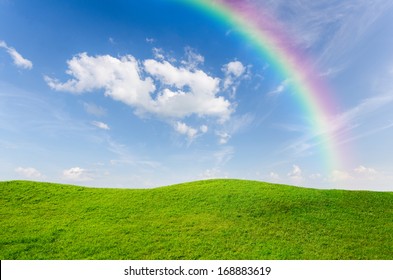 Green Grass With Blue Sky And Rainbow As Background 