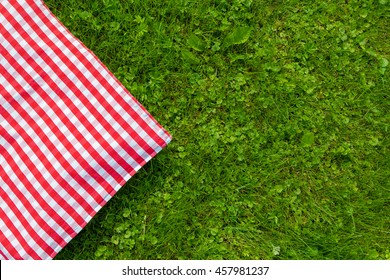 Green grass and checkered tablecloth background for picnic, top view