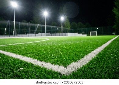 Green grass field background for football and soccer sports, volleyball, evening stadium, artificial lighting. Green lawn pattern and texture background. Close-up image