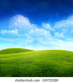 Green Grass Field On Small Hills And Blue Sky With Clouds