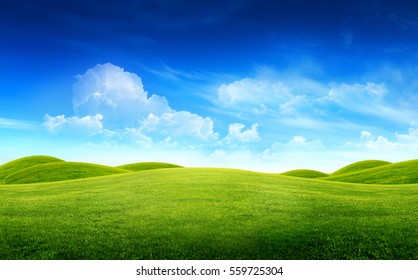 Green grass field on small hills and blue sky with clouds - Powered by Shutterstock