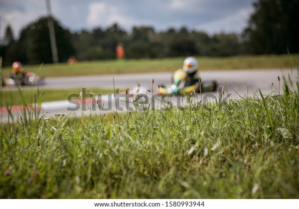 Green grass in foreground and\
go kart in background at the sports go kart event in Smiltene,\
Latvia\
