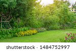 Green grass lawn in a garden with random pattern of grey concrete stepping stone , Flowering plant, shurb , trees on backyard under morning sunshine with good care landscaping in a pubblic park  