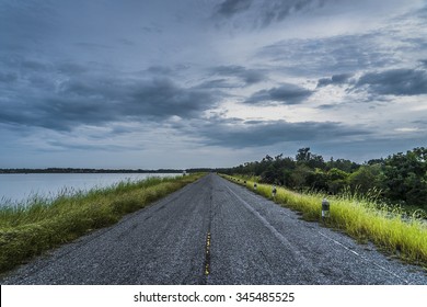 green grass with local roadway beside the lake while storm
