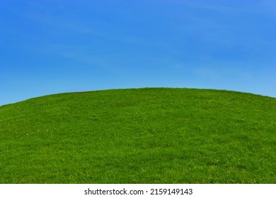 A Green Grassy Hill Against A Blue Sky.