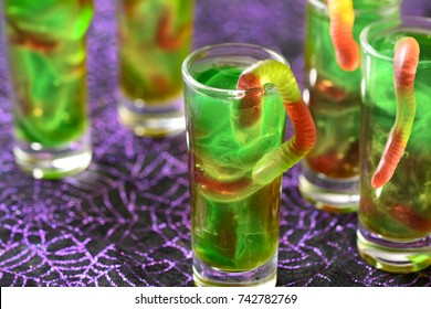 Green Halloween Jello Shots With Gummy Worms On The Purple Background